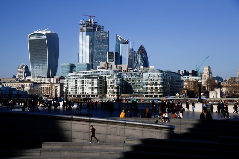 FILE PHOTO: The financial district can be seen as a person runs in the sunshine on London's south bank
