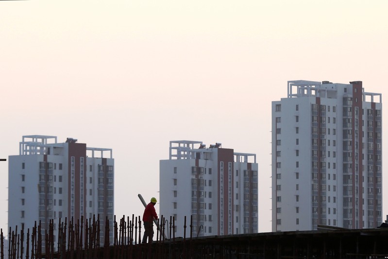 FILE PHOTO: Worker stands on the scaffolding at a construction site against a backdrop of residential buildings in Huaian
