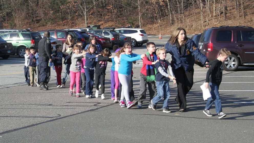 Two Connecticut State Police officers escort a class of students and two adults out of Sandy Hook Elementary School in Newtown, Conn., Dec. 14, 2012, after a shooter entered the building and killed 20 children and six adults before taking his own life.