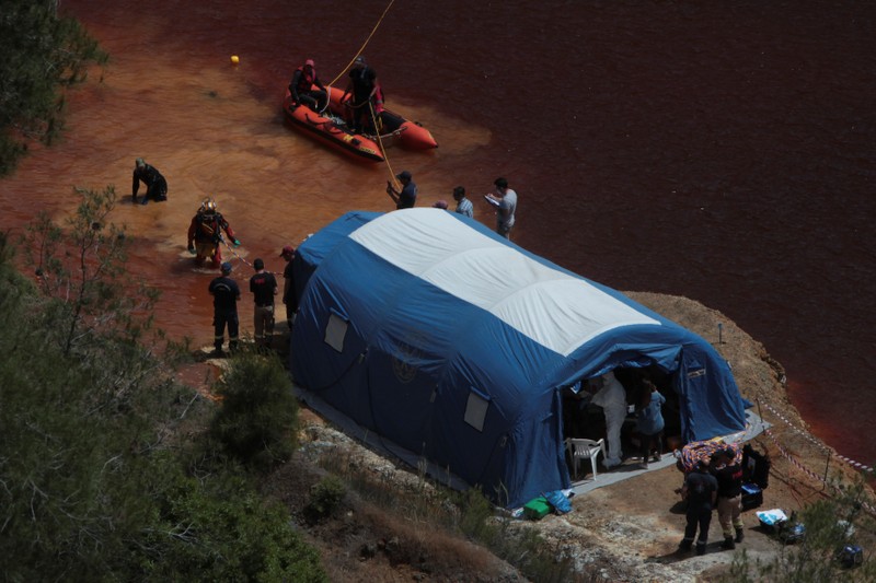 Police forensics officers, rescuers and divers retrieve a suitcase near the village of Mitsero