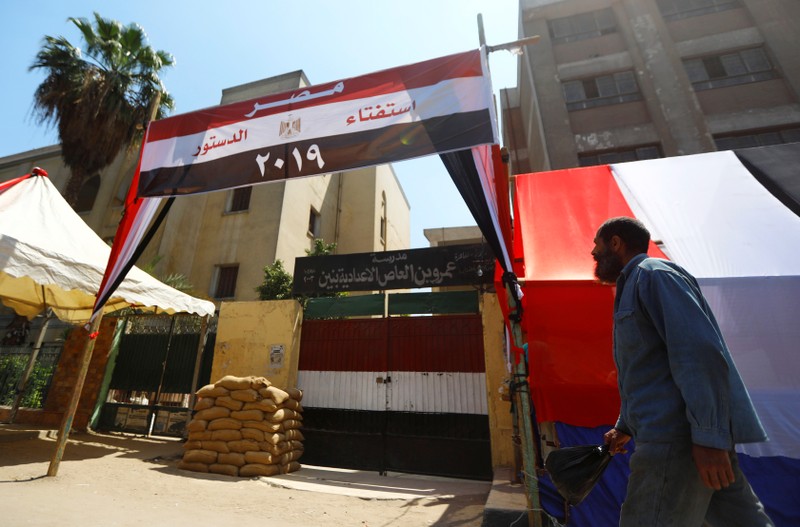 An Egyptian man walks in front of a school used as a polling station covered from outside by Egyptian flags, during the preparations for the upcoming referendum on constitutional amendments in Cairo