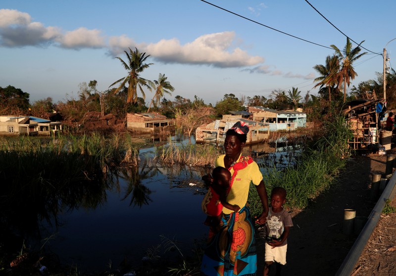 A woman walks with her children past flooded houses in the aftermath of Cyclone Idai in Tica near Beira,