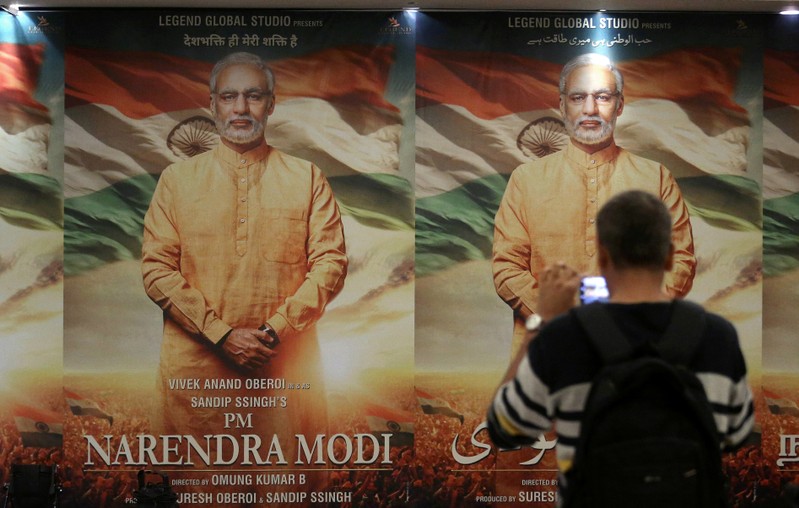FILE PHOTO: A man uses his mobile phone to take photographs of a poster of the upcoming film 