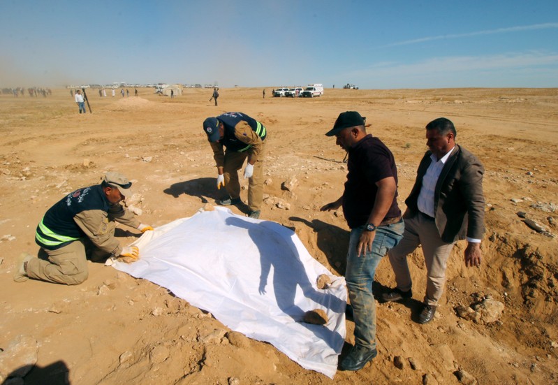 Iraqi members of the Civil Defense cover the bones from an unearthed mass grave of Kurds in west of the city of Samawa