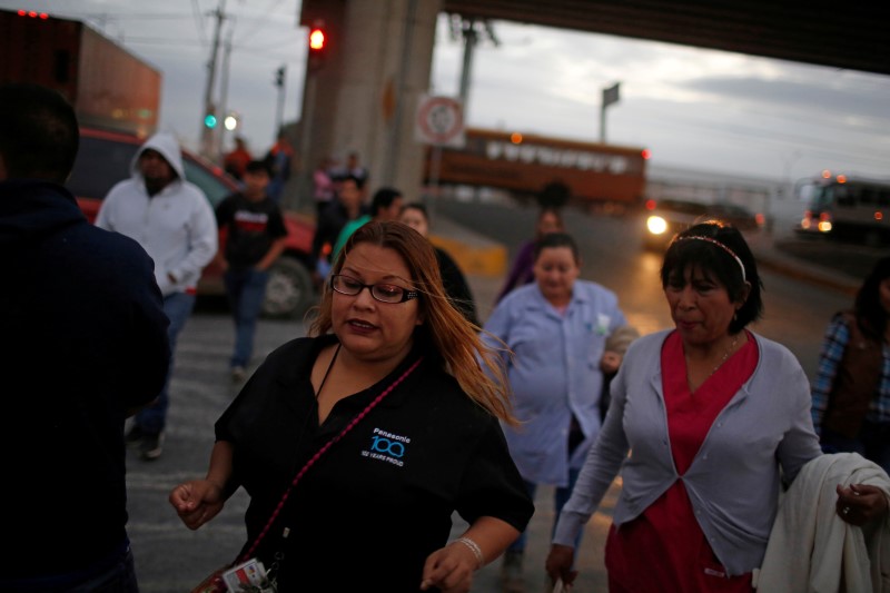 FILE PHOTO: Workers of assembly factories cross a street as they rush toward their shift at an industrial park in Reynosa