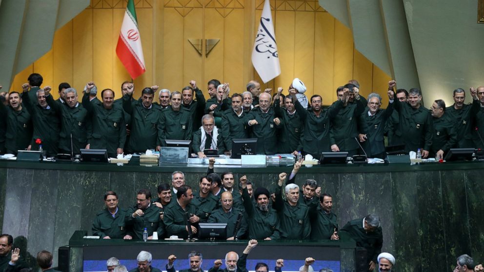 Wearing the uniform of the Iranian Revolutionary Guard, lawmakers chant slogans during an open session of parliament in Tehran, Iran, Tuesday, April 9, 2019.