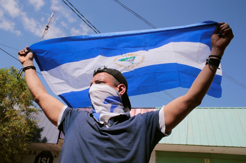 A demonstrator holds a national flag during a march to mark the one year anniversary of the protests against Nicaraguan President Daniel Ortega's government, in Managua