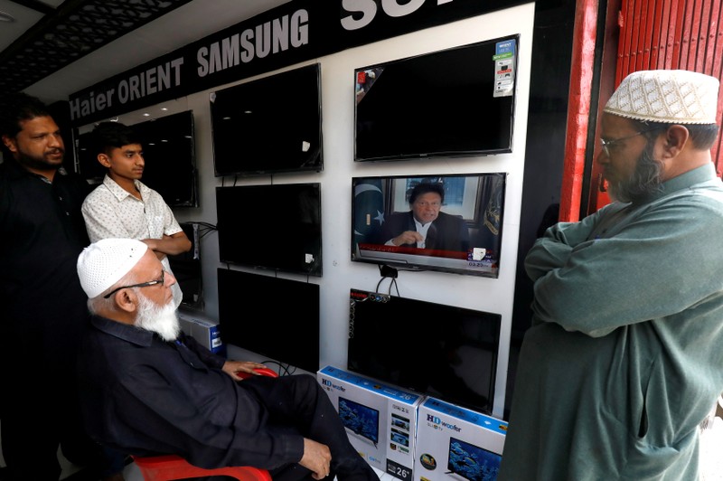 FILE PHOTO: Shopkeepers watch the speech of Pakistani Prime Minister Imran Khan, after Pakistan shot down two Indian military aircrafts, at a shop selling television screens in Karachi