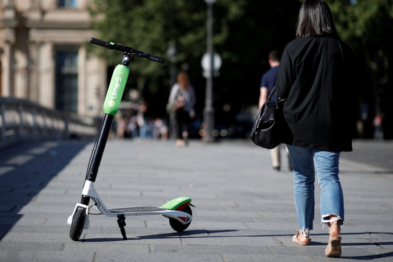 FILE PHOTO: A woman walks past a dock-free electric scooter Lime-S by California-based bicycle sharing service Lime displayed on their launch day in Paris