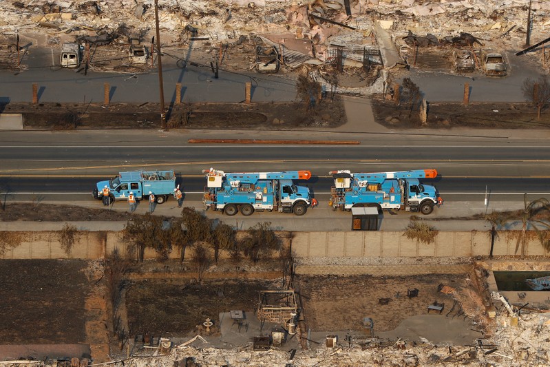 FILE PHOTO: Pacific Gas and Electric (PG&E) trucks are seen parked on a road between homes destroyed by the Tubbs Fire in Santa Rosa, California