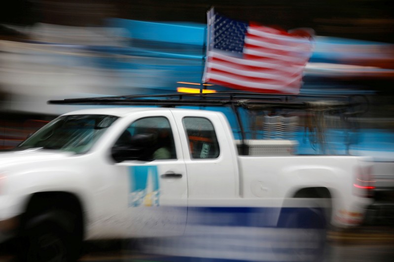 FILE PHOTO: A PG&E truck carrying an American Flag drives past PG&E repair trucks in Paradise