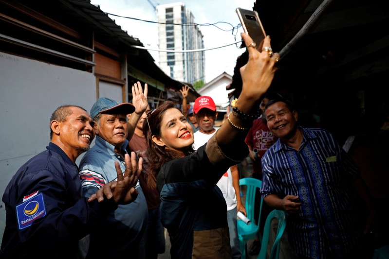 Shanti Ramchand, a candidate for the next parliamentary election from Nasdem (National Democratic) party, takes a selfie with her supporters during her campaign trail at a hutment area south of Jakarta