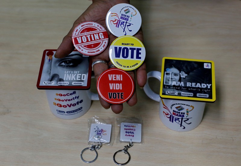 An election official displays badges, key chains and mugs to be distributed among the people to encourage them to cast their vote, in Kolkata
