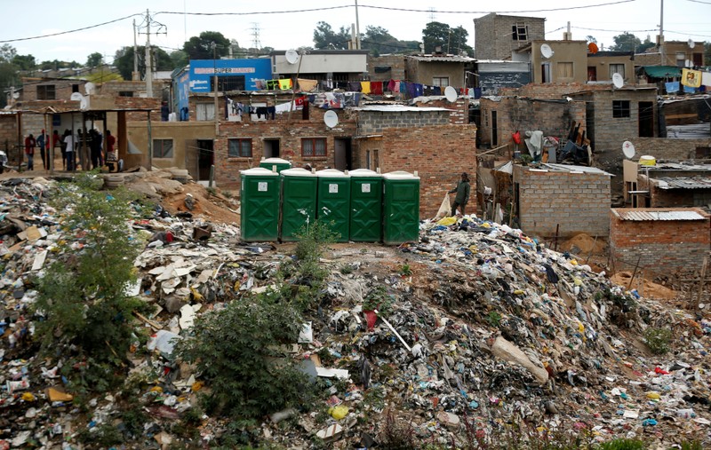 Man stands near public toilets placed on a dump site in Alexandra township