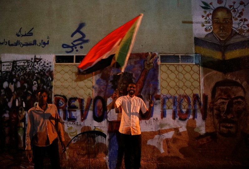 A Sudanese protester waves a national flag as he arrives a mass protest in front of the Defence Ministry in Khartoum