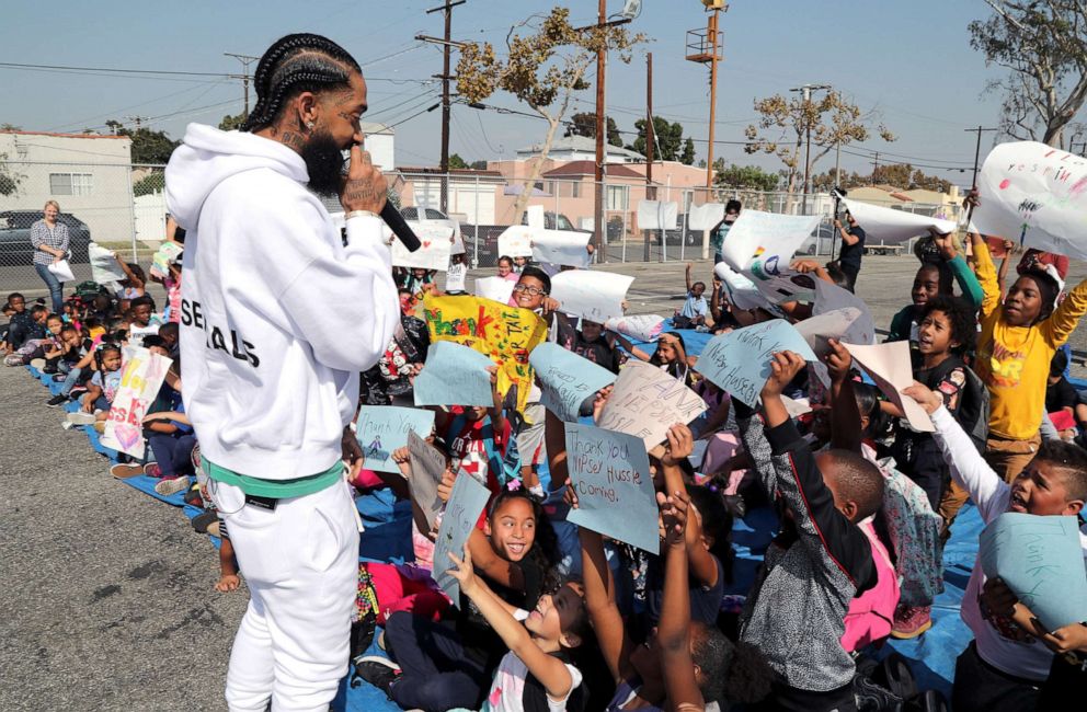 Rapper Nipsey Hussle speaks to kids after the opening of a basketball court, Oct. 22, 2018 in Los Angeles. Hussle partnered with Puma to refurbish the elementary school basketball court in south Los Angeles near where Nipsey grew up.