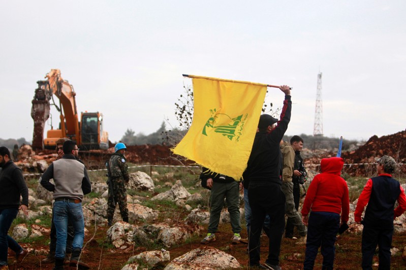 A man holds a Hezbollah flag at Meis al-Jabal village