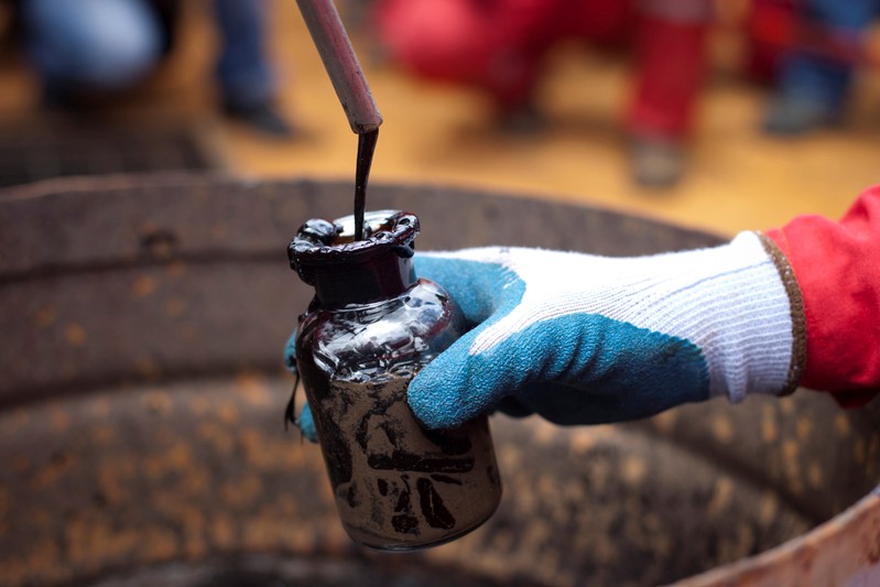 FILE PHOTO: A worker collects a crude oil sample at an oil well operated by Venezuela's state oil company PDVSA in Morichal