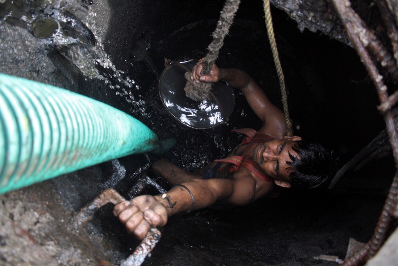 FILE PHOTO: A labourer cleans an underground sewer at Noida