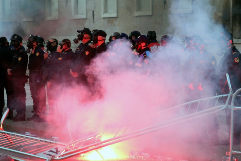 A burning flambeau is pictured in front of a police formation during an anti-government protest in front of Prime Minister Edi Rama's office in Tirana