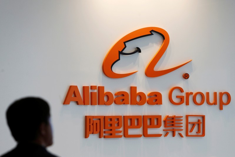 A man stands near the logo of Alibaba Group at the company's newly-launched office in Kuala Lumpur