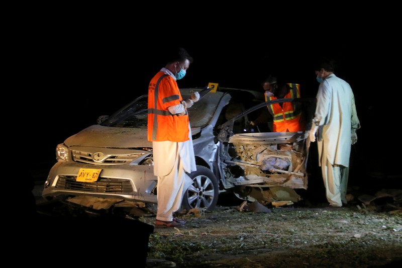 Members of the bomb disposal unit survey a damaged vehicle at the site after a blast near a mosque in Quetta,