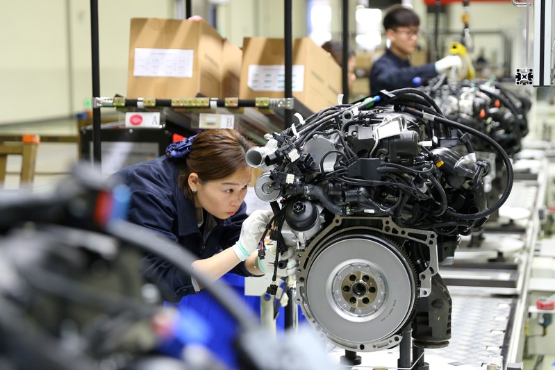 FILE PHOTO: Employees work on the production line at a factory of automotive engine manufacturer Power Xinchen in Mianyang