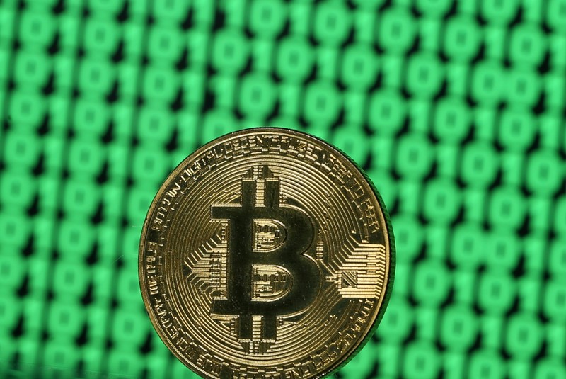 FILE PHOTO: Bitcoin token is seen placed on a monitor that displays binary digits in this illustration picture