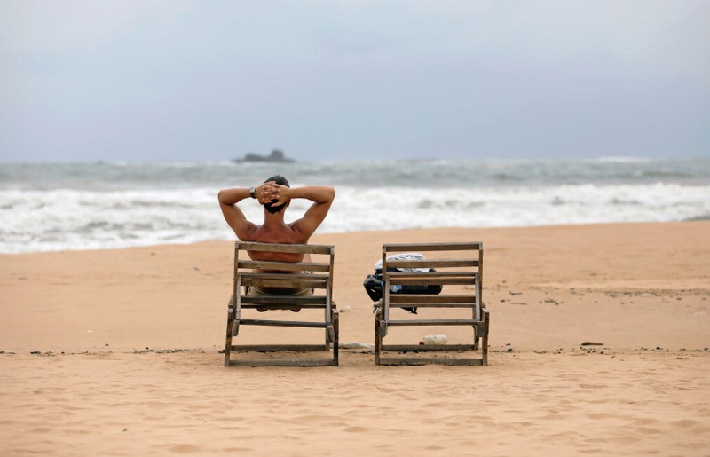 A tourist rests on a beach near hotels in a tourist area in Bentota