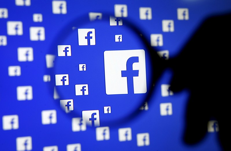 FILE PHOTO: A man poses with a magnifier in front of a Facebook logo on display in this illustration taken in Sarajevo