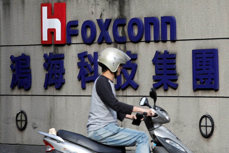 FILE PHOTO: A motorcyclist rides past the logo of Foxconn, the trading name of Hon Hai Precision Industry, in Taipei