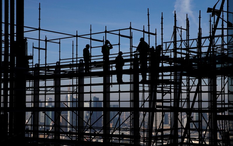FILE PHOTO: Construction workers are silhouetted while standing on scaffolding at the construction site of the new headquarters of the ECB during a guided media tour in Frankfurt