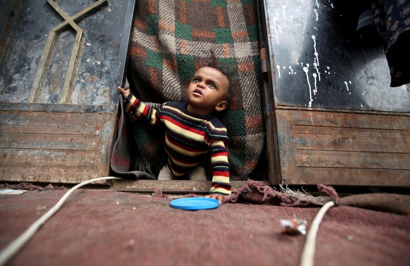 FILE PHOTO: A displaced child from Yemen's Red Sea port city of Hodeida looks out from the door of his family's shelter in Sanaa