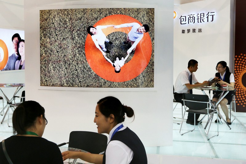Staff members are seen at the booth of Baoshang Bank at an investment and finance fair for small and medium sized enterprises in Beijing