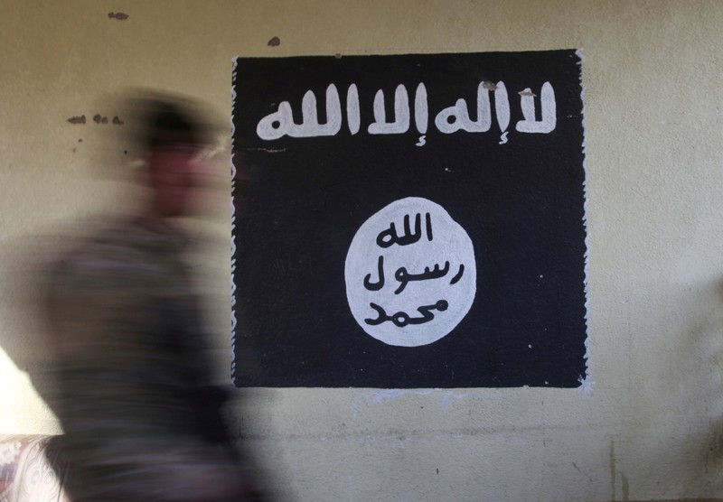 FILE PHOTO: A member of the Iraqi rapid response forces walks past a wall painted with the black flag commonly used by Islamic State militants, during a battle in the Wahda district of Mosul