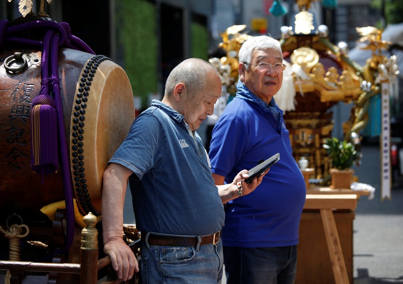 FILE PHOTO: A man uses his smartphone next to a Japanese traditional Taiko drum during the preprartion for the upcoming Kanda festival in Tokyo