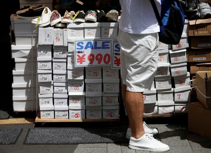 A shopper looks at shoes next to signs advertising sales at a shopping district in Tokyo
