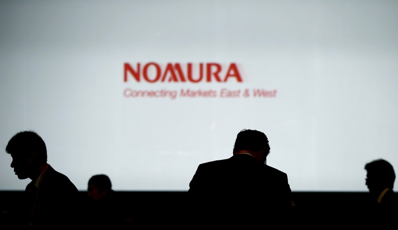 File photo of investors standing in front of a screen showing the logo of Nomura Holdings in Tokyo