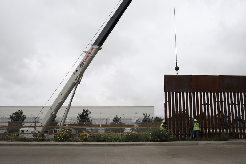 Workers replace a section of the border fence between U.S. and Mexico, as seen from Tijuana