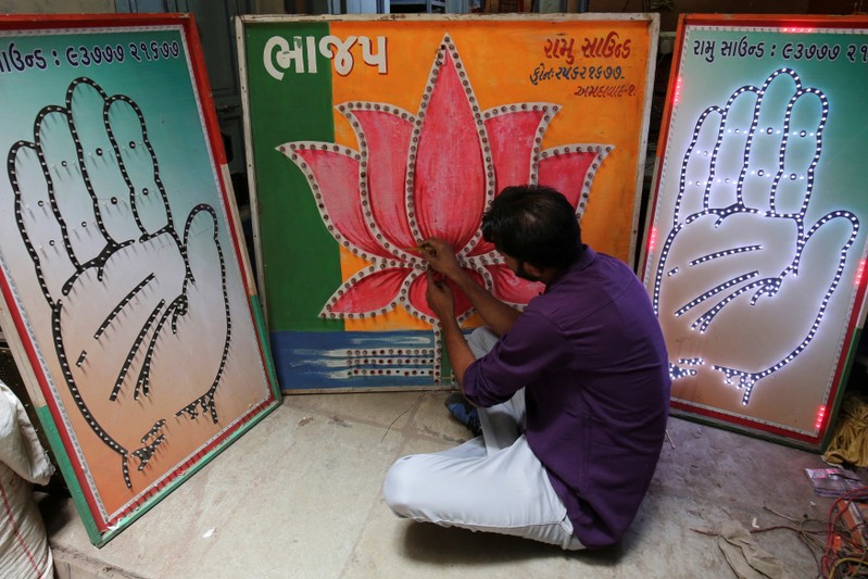 FILE PHOTO - An electrician tests LED-light fitted boards with symbols of India's ruling Bharatiya Janata Party and main opposition Congress party at a workshop in Ahmedabad