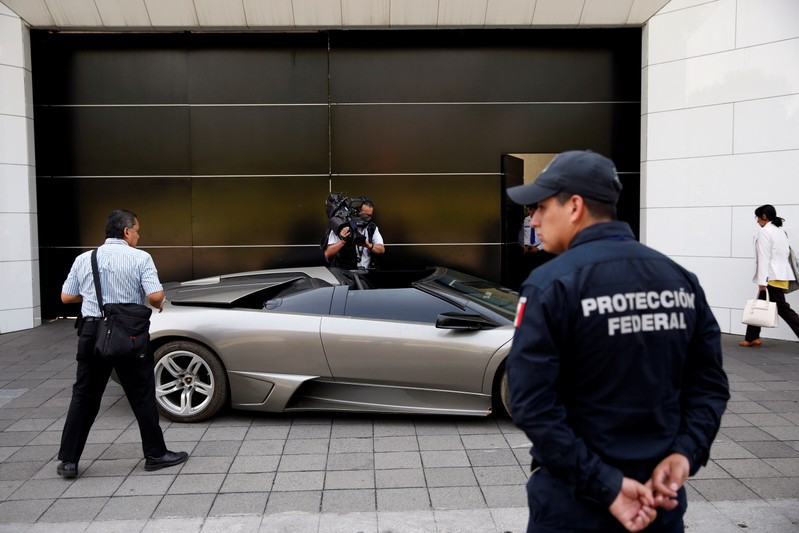 A police officer stands near a Lamborghini Murcielago 2007, part of the fleet of vehicles seized by the government from politicians and organized crime as part of an auction in Mexico City