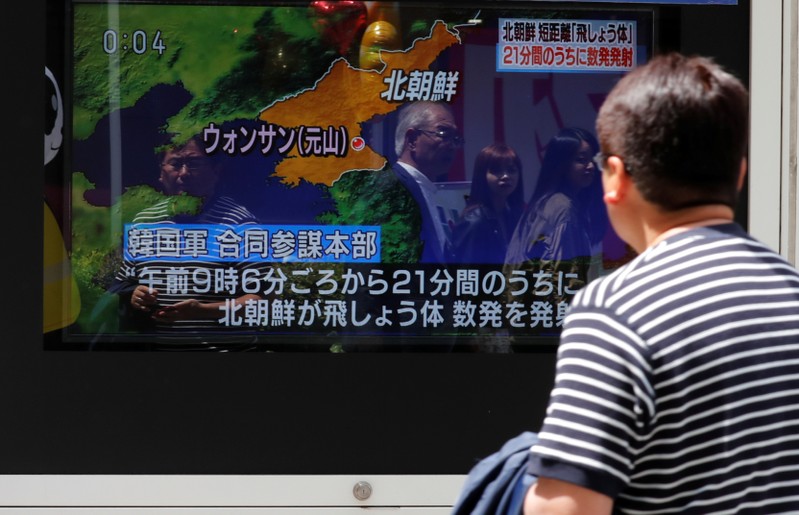 A man watches a television screen showing a news report on North Korea firing several short-range projectiles from its east coast, in Tokyo