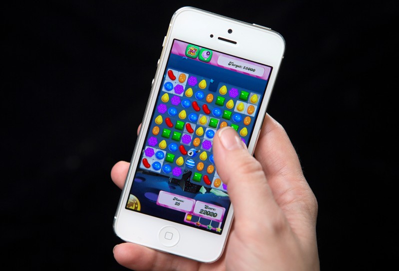 FILE PHOTO: A woman poses for a photo illustration with an iPhone as she plays Candy Crush in New York