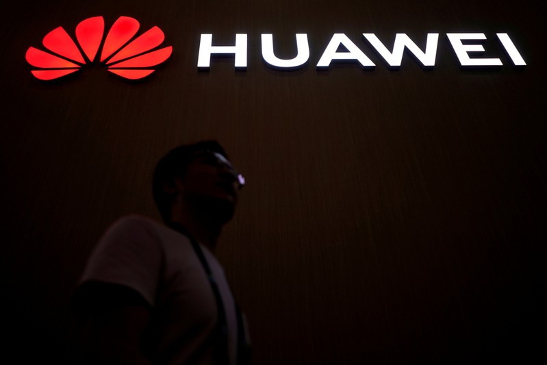 FILE PHOTO: A man walks past a sign board of Huawei at CES (Consumer Electronics Show) Asia 2018 in Shanghai
