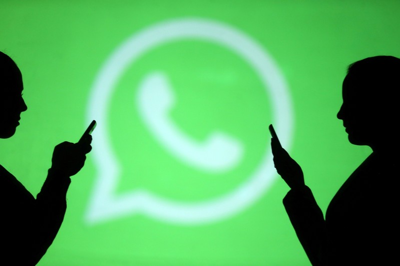 FILE PHOTO: Silhouettes of mobile users are seen next to a screen projection of Whatsapp logo in this picture illustration