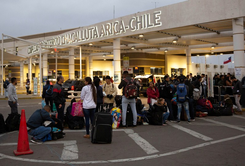 People are seen in a row at the Chacalluta border crossing between Chile and Peru, in Arica, Chile