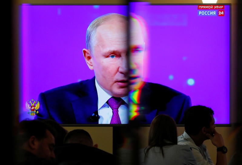 Russian President Putin is seen on a screen at a press centre during a televised phone-in show in Moscow