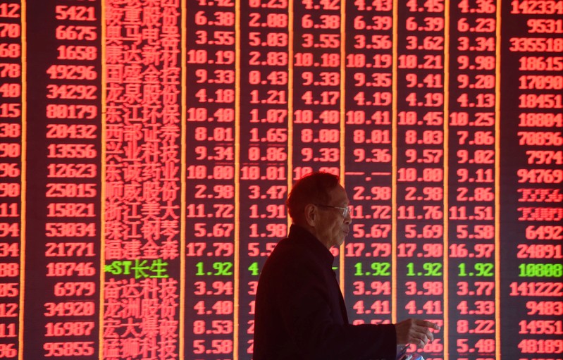 Man is seen in front of an electronic board showing stock information on the first day of trading in the Year of the Pig at a brokerage house in Hangzhou