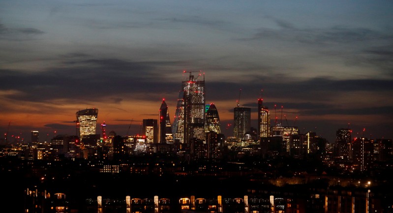 FILE PHOTO: The sun sets behind the financial district of London, Britain.