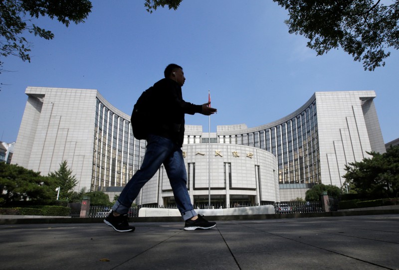 A man walks past the headquarters of the PBOC, the central bank, in Beijing